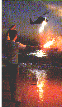 man holding flare on the beach while looking at Coast Guard helicopter